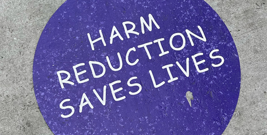 "Harm Reduction Saves Lives" painted on a sidewalk